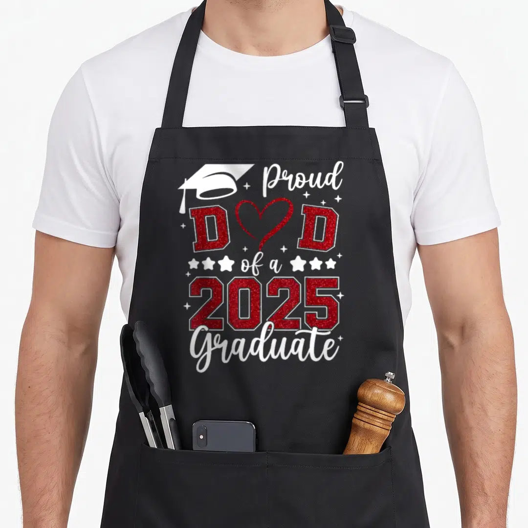 Proud senior family aprons - Red glitter text Proud DAD of a 2025 Graduate with white cap and heart symbol — shown on a black cotton canvas apron against a white background