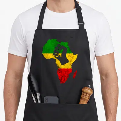 Rastafari hippie apron - Distressed Africa map with green yellow red bands and grey raised fist silhouette — shown on a black cotton canvas apron against a white background