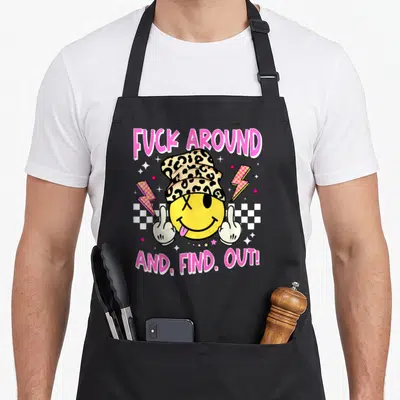 Around leopard apron - Cartoon smiley face in leopard hat holding two middle fingers with pink text and checkered — shown on a black cotton canvas apron against a white background