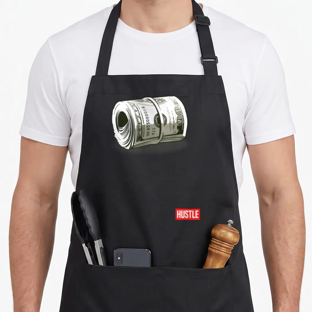 Hustle money apron - Realistic cash roll with rubber band and HUSTLE text in red box — shown on a black cotton canvas apron against a white background