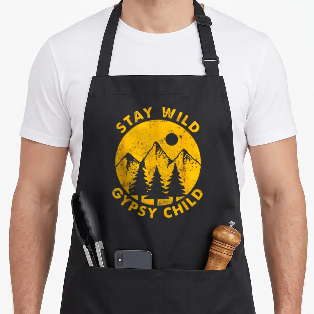 Gypsy bohemian apron - Yellow circle with mountains and pine trees and STAY WILD GYPSY CHILD text — shown on a black cotton canvas apron against a white background