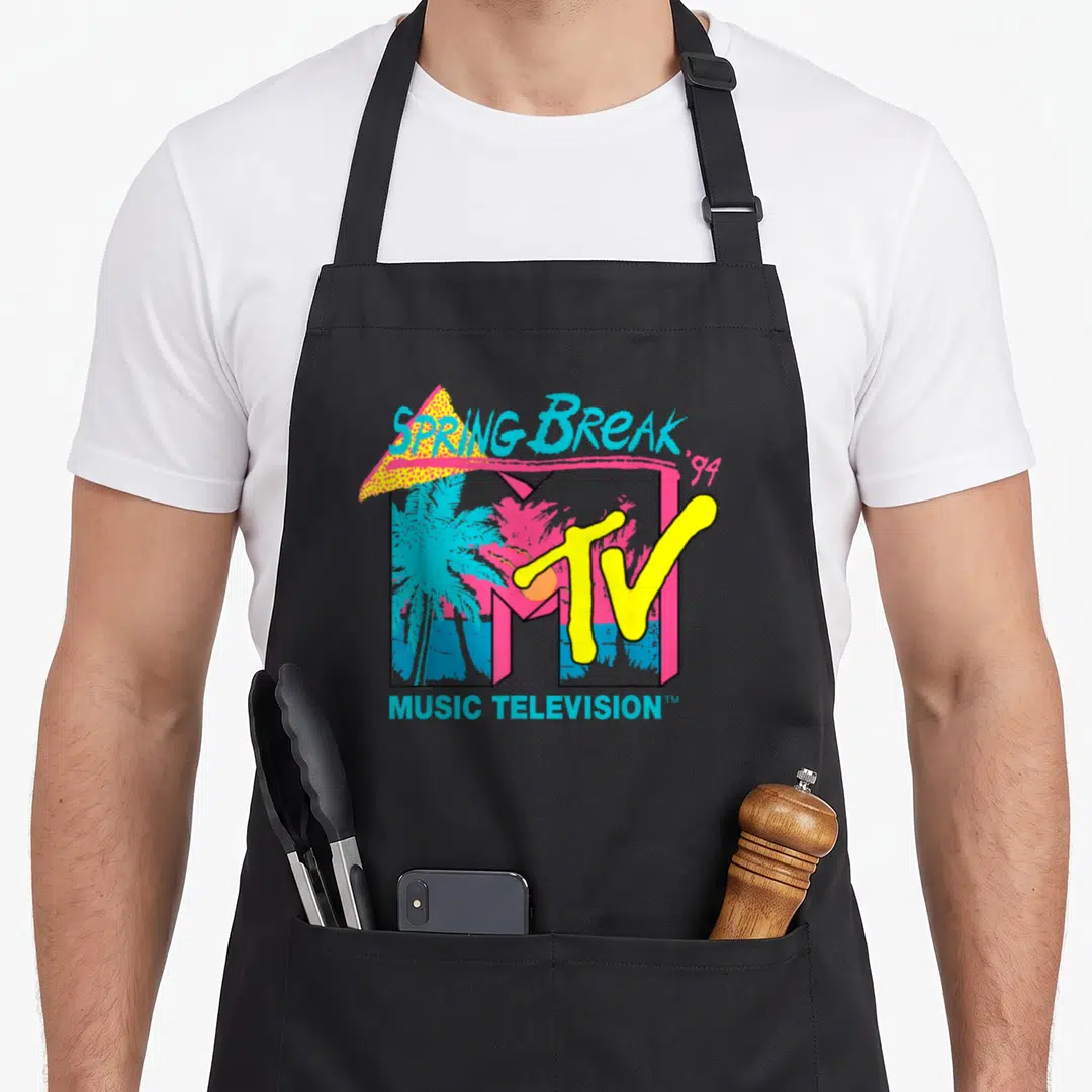 Break spring aprons - Retro 1994 MTV logo with palm trees and Spring Break text in pink blue yellow orange — shown on a black cotton canvas apron against a white background