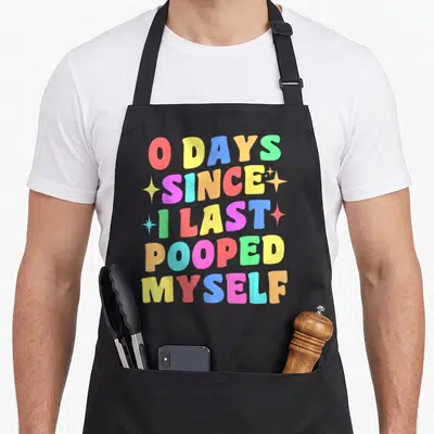 Myself gag aprons - Stacked rainbow text 0 DAYS SINCE I LAST POOPED MYSELF with four scattered stars — shown on a black cotton canvas apron against a white background