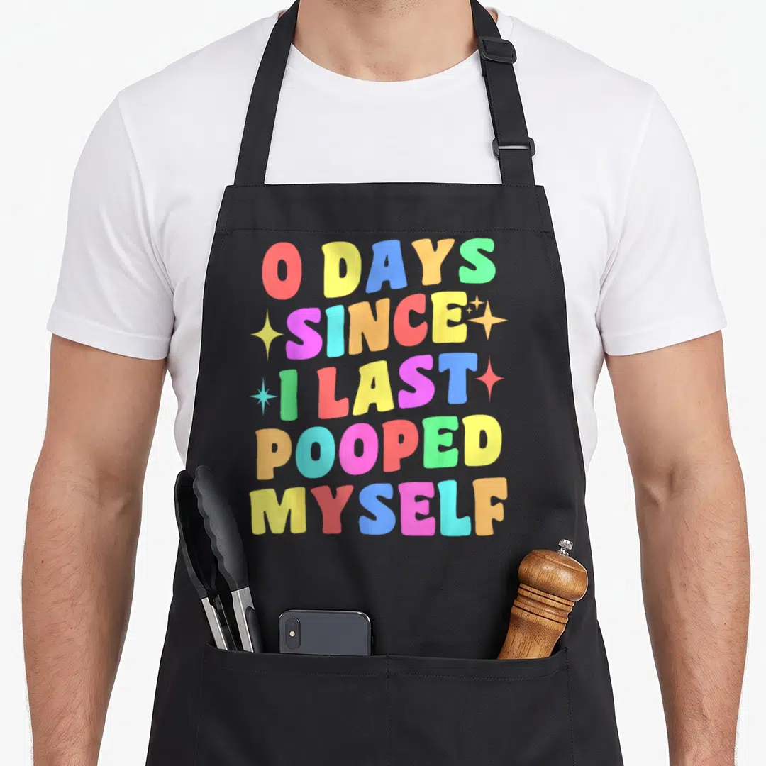 Myself gag aprons - Stacked rainbow text 0 DAYS SINCE I LAST POOPED MYSELF with four scattered stars — shown on a black cotton canvas apron against a white background
