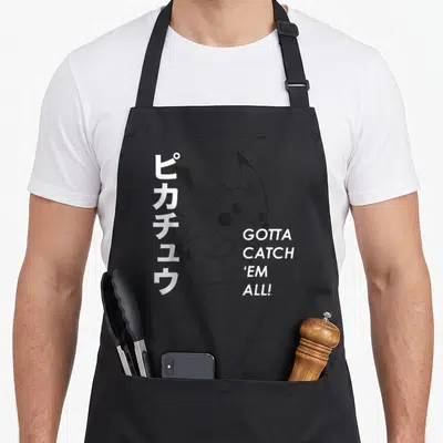 Catch poke addict apron - Minimalist grey Pikachu with vertical Japanese text and stacked Gotta Catch Em All lettering — shown on a black cotton canvas apron against a white background