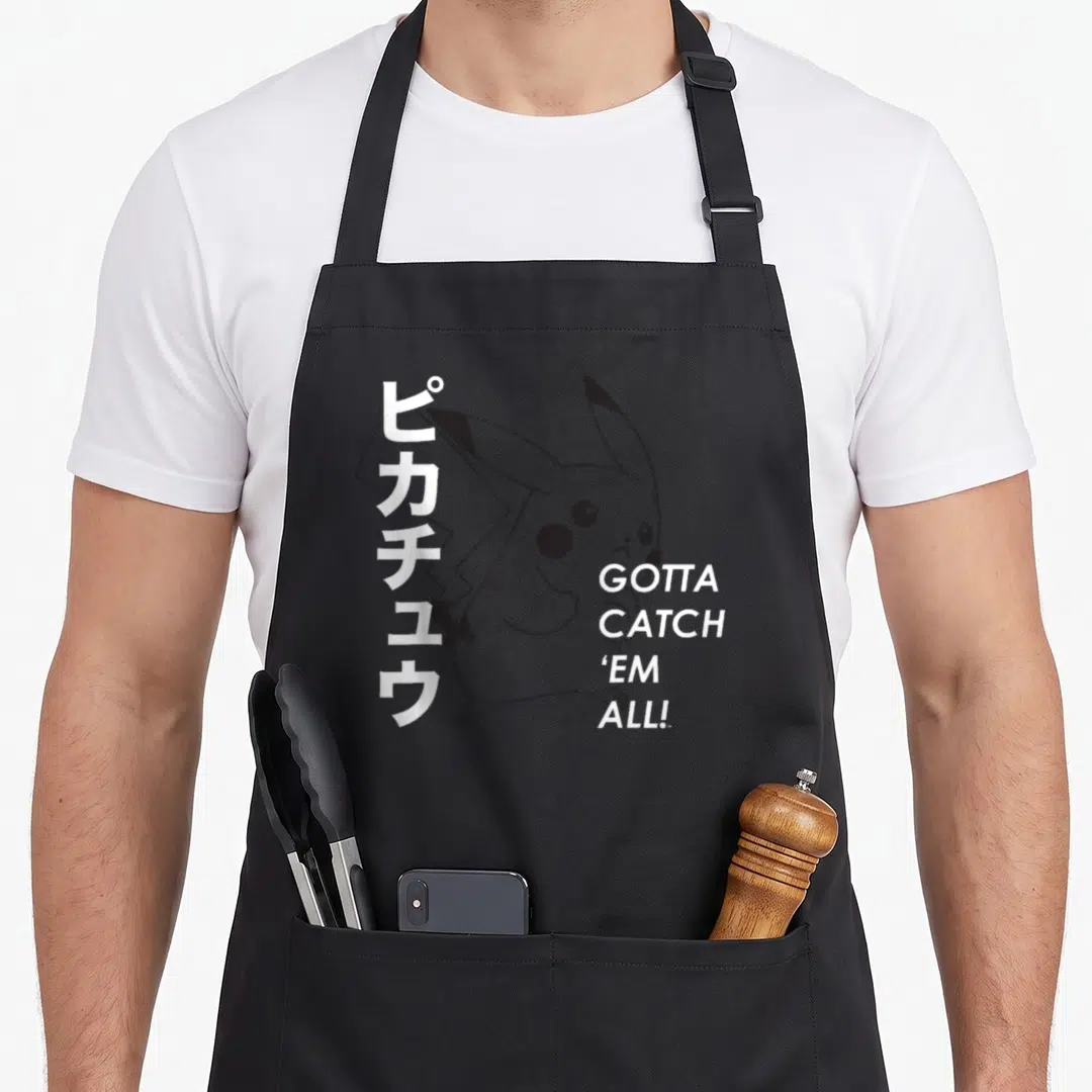 Catch poke addict apron - Minimalist grey Pikachu with vertical Japanese text and stacked Gotta Catch Em All lettering — shown on a black cotton canvas apron against a white background