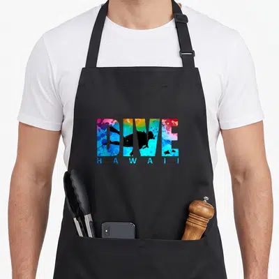 Hawaii diving apron - DIVE HAWAII watercolor text with diver and fish silhouettes in blue yellow red teal black — shown on a black cotton canvas apron against a white background