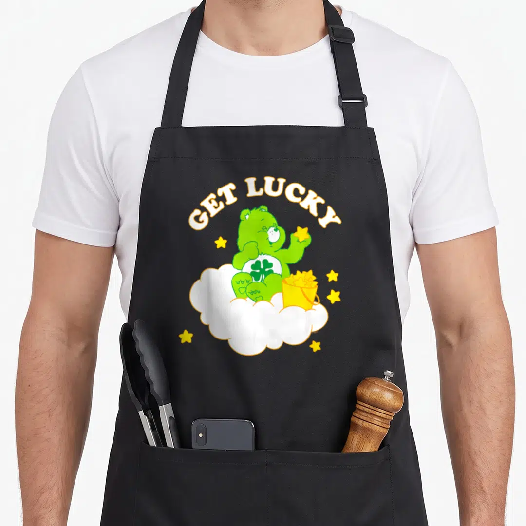 Luck lucky apron - Green bear on white cloud holding yellow star next to gold bucket under arched text — shown on a black cotton canvas apron against a white background