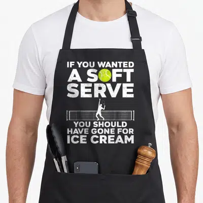 Funny player tennis apron - Tennis player silhouette hitting ball over net with white distressed text and yellow-green — shown on a black cotton canvas apron against a white background