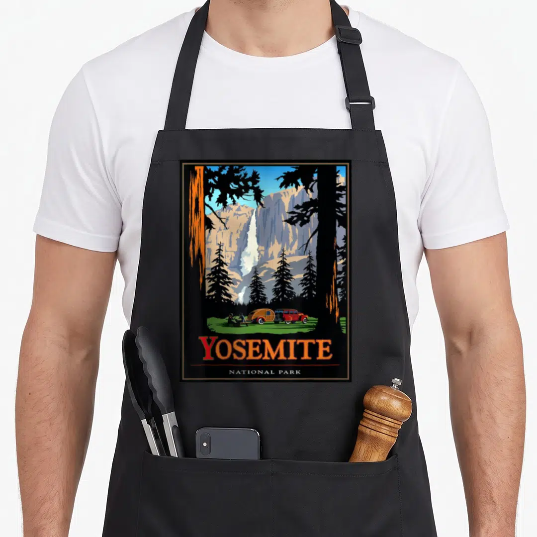 Park yosemite apron - Retro Yosemite poster with waterfall, vintage truck, and orange text on black background — shown on a black cotton canvas apron against a white background