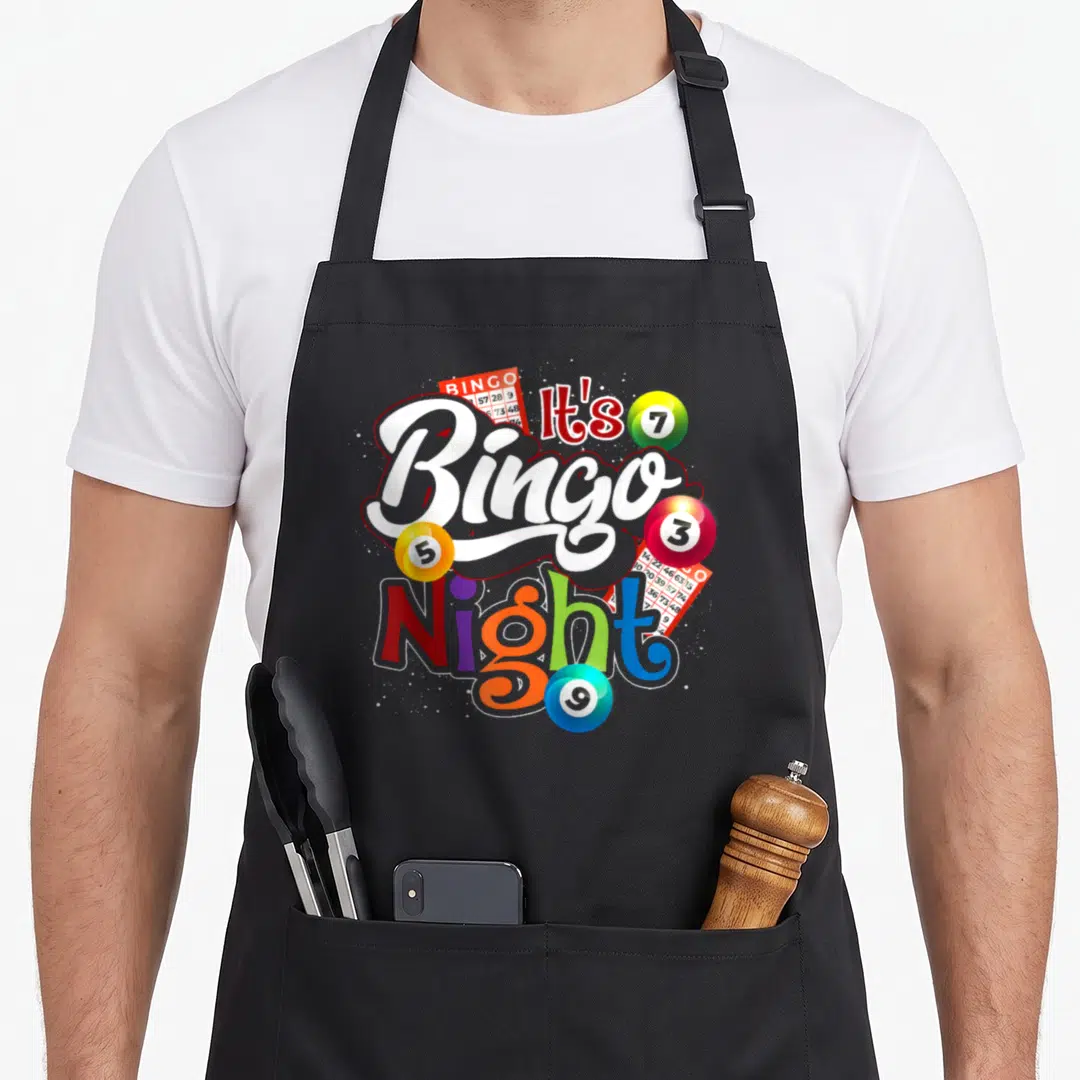 Night bingo apron - It's Bingo Night text with colorful numbered balls and bingo cards — shown on a black cotton canvas apron against a white background