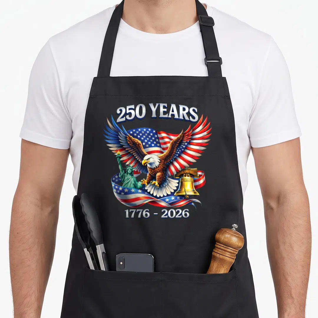 Anniversary years freedom apron - Bald eagle over waving flag with Statue of Liberty and Liberty Bell, 250 YEARS text — shown on a black cotton canvas apron against a white background