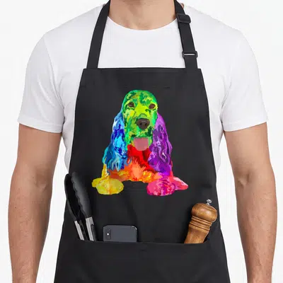 Cute dog cocker spaniel apron - Rainbow colored Cocker Spaniel dog illustration in green, blue, purple, red, and yellow — shown on a black cotton canvas apron against a white background