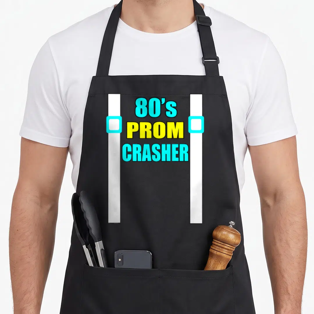 Crasher 80s apron - Stacked 80's Prom Crasher text in cyan and yellow with white suspender bars — shown on a black cotton canvas apron against a white background