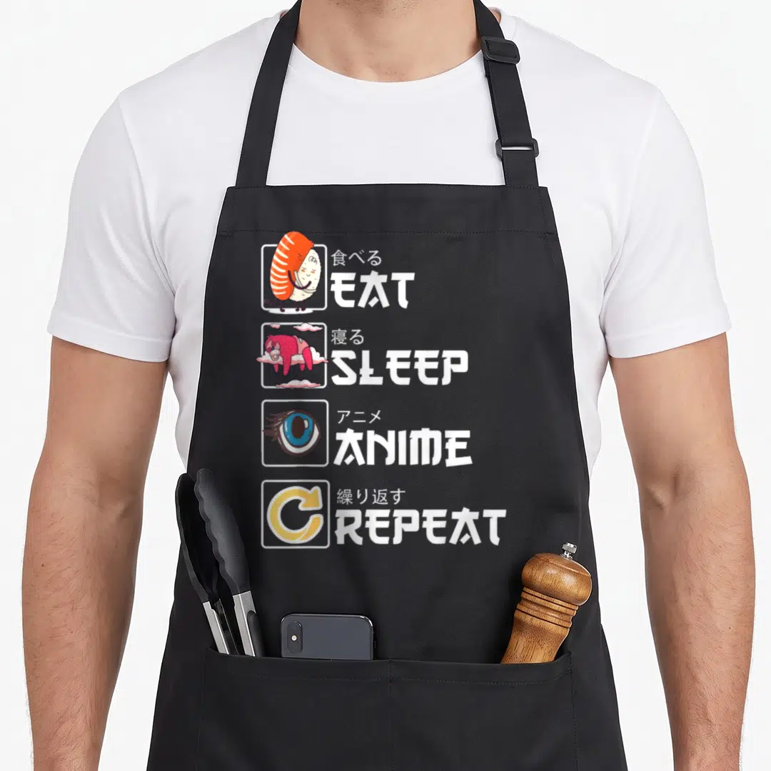 Kawaii sushi apron - Four square icons showing shrimp, sleep, eye, repeat with Japanese and English text — shown on a black cotton canvas apron against a white background