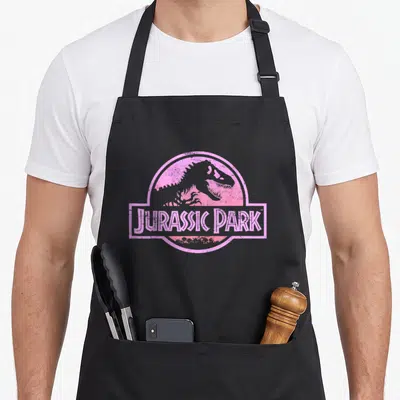Neon novelty apron - Pink dinosaur silhouette in circle with JURASSIC PARK text banner overlay — shown on a black cotton canvas apron against a white background