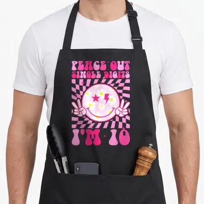 Peace custom face apron - Retro smiley face with peace hands and I'M 10 text on pink checkerboard — shown on a black cotton canvas apron against a white background