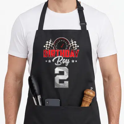 Pit 2nd apron - Speedometer checkered flags BIRTHDAY Boy 2 tire track print — shown on a black cotton canvas apron against a white background