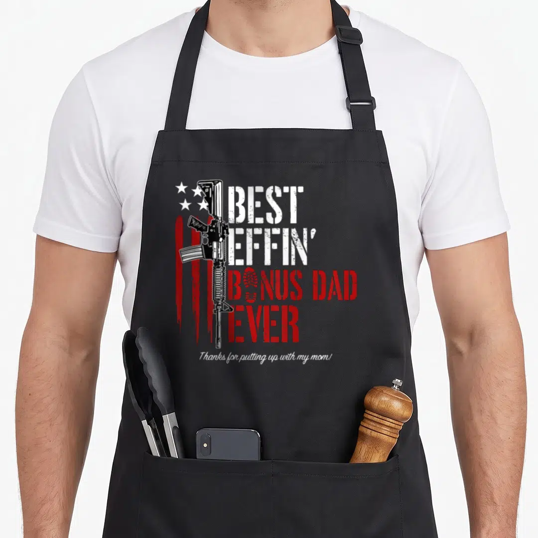 Effin novelty apron - Vertical rifle next to stacked text BEST EFFIN BONUS DAD EVER with red stripes and stars — shown on a black cotton canvas apron against a white background