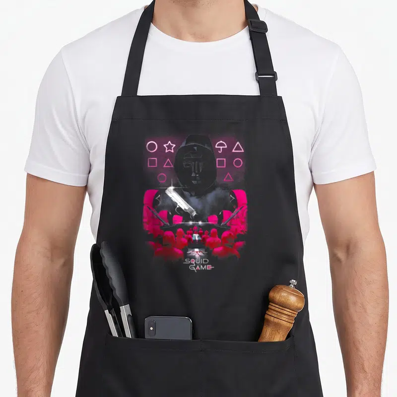 Geometric crazy squid man apron - Pink masked guards, gun, geometric shapes, SQUID GAME text, distressed grey background — shown on a black cotton canvas apron against a white background
