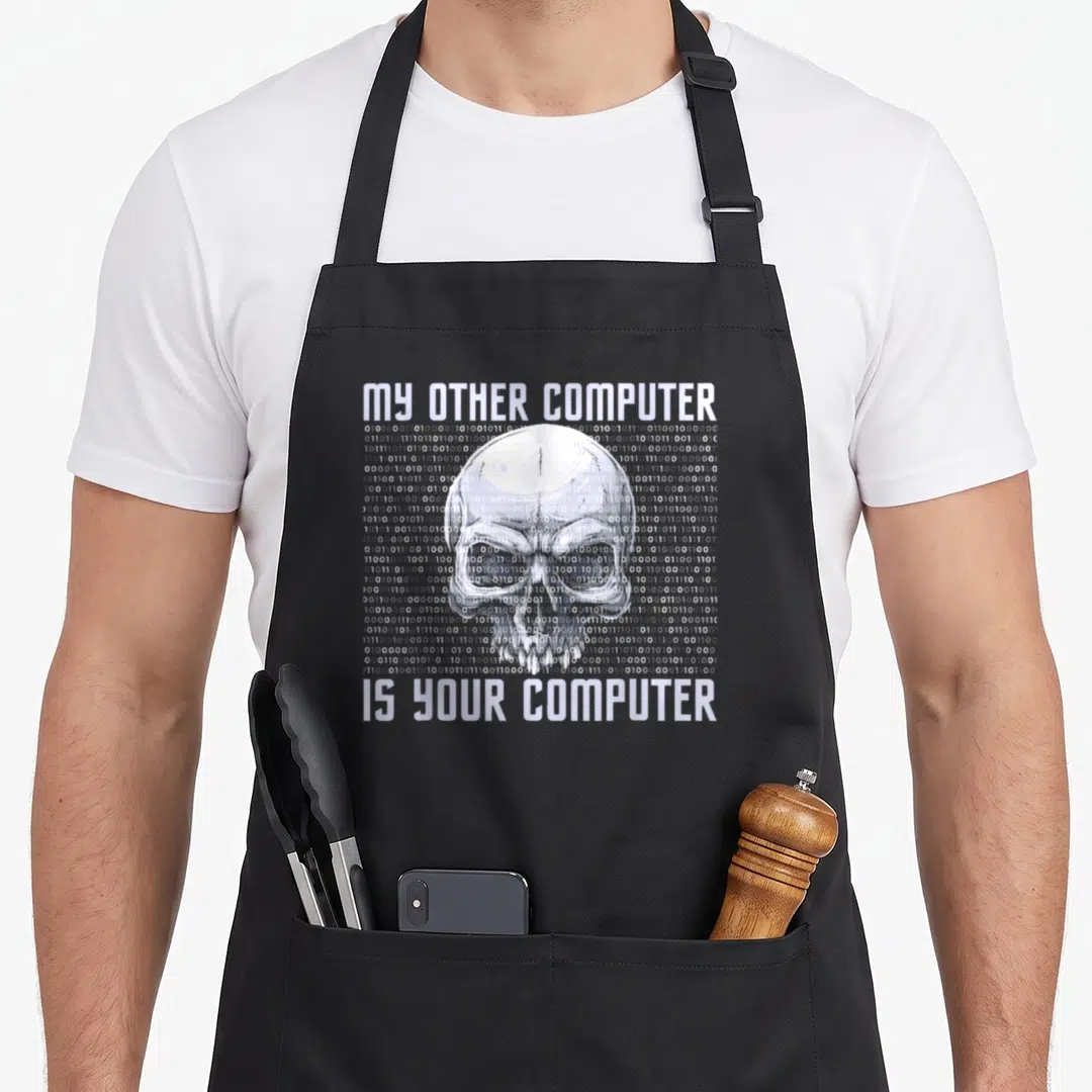 Computer analyst cybersecurity apron - White skull made of binary code with text MY OTHER COMPUTER IS YOUR COMPUTER — shown on a black cotton canvas apron against a white background