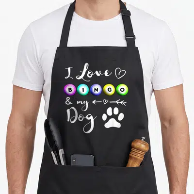 Bingo dog apron - I Love BINGO & my Dog text with colorful balls and white paw print — shown on a black cotton canvas apron against a white background