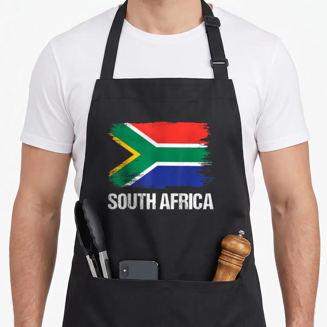 Pride south african apron - Distressed South African flag in red green blue yellow white above white text SOUTH AFRICA — shown on a black cotton canvas apron against a white background