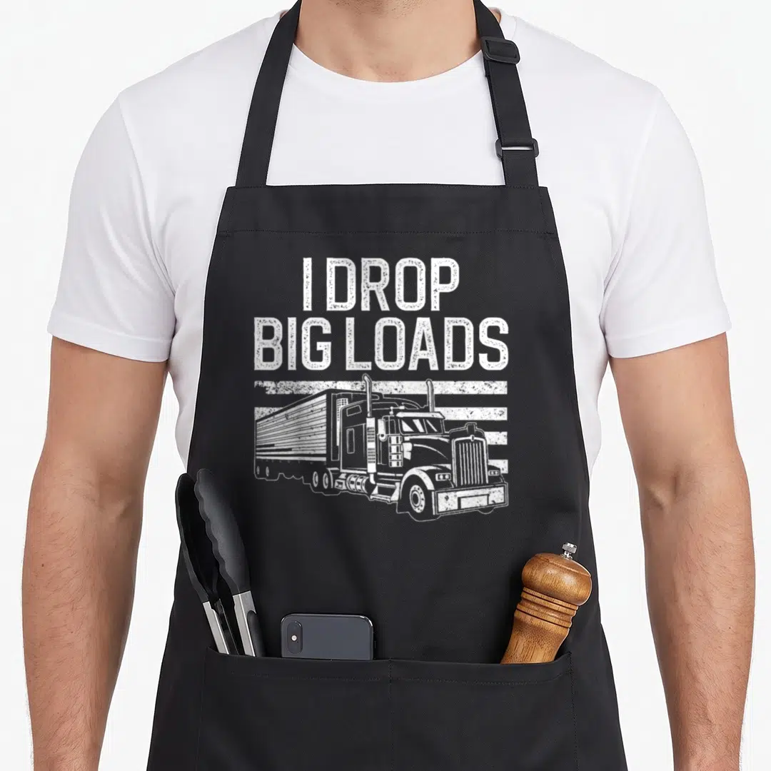 Funny trucker semi truck apron - I DROP BIG LOADS text above distressed white semi-truck on horizontal lines — shown on a black cotton canvas apron against a white background