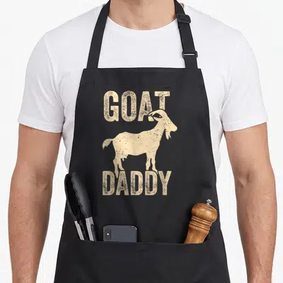 Goat daddy father day apron - Distressed tan goat silhouette between GOAT and DADDY text — shown on a black cotton canvas apron against a white background