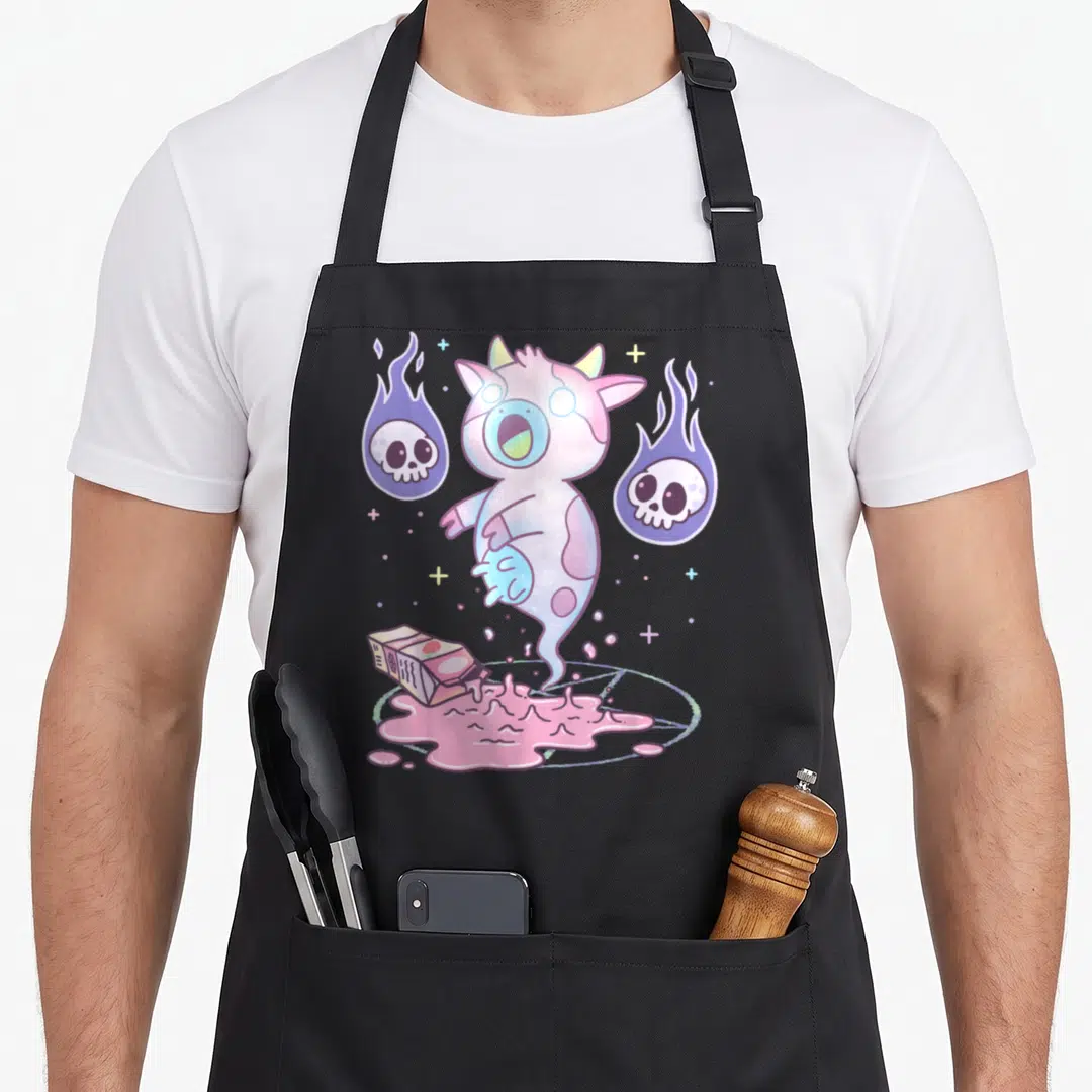Pastel milk aprons - Ghost cow floating above pink puddle and tipped carton with two flaming skulls and crosses — shown on a black cotton canvas apron against a white background