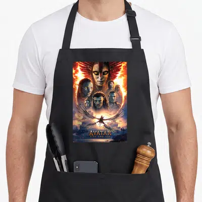 Avatar fire girl apron - Na'vi faces in fire collage with winged rider and AVATAR FIRE AND ASH text at bottom — shown on a black cotton canvas apron against a white background