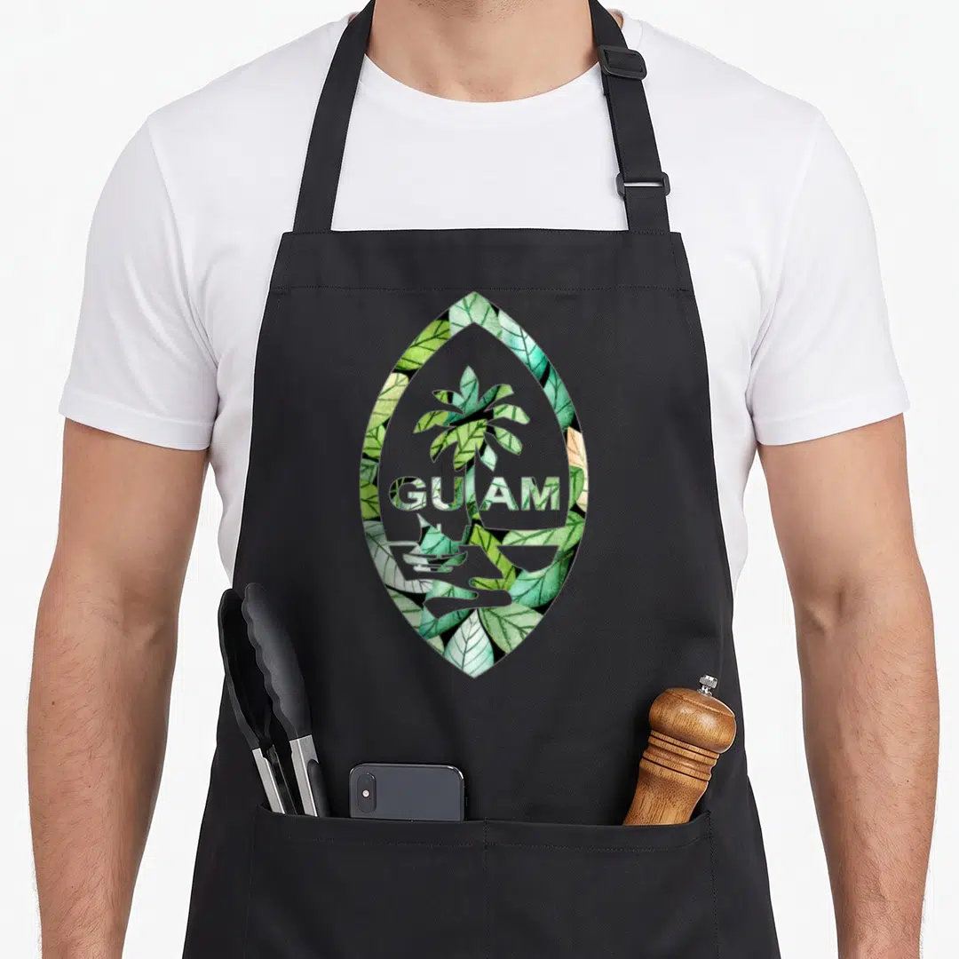 Seal guam aprons - Watercolor palm tree and GUAM text inside a green leaf-shaped frame — shown on a black cotton canvas apron against a white background