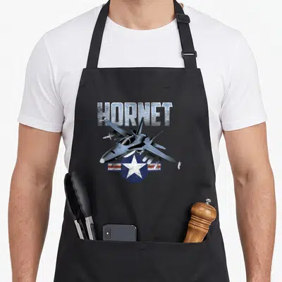 Warbird airplane apron - HORNET text above grey fighter jet over blue white and red star emblem — shown on a black cotton canvas apron against a white background