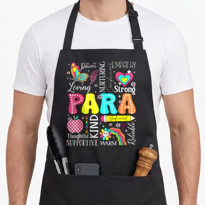 Para school apron - PARA in polka dots surrounded by Patient Nurturing Empathy butterfly and heart icons — shown on a black cotton canvas apron against a white background
