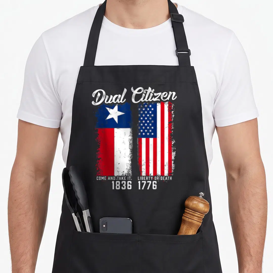Dual texans apron - Dual Citizen text above distressed Texas and US flags with dates 1836 and 1776 — shown on a black cotton canvas apron against a white background