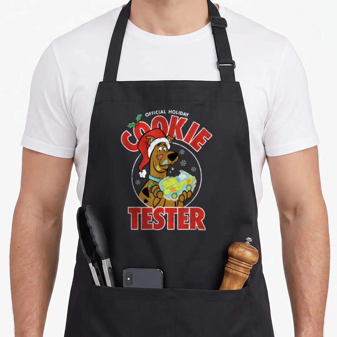 Tester christmas cookie apron - Scooby-Doo in Santa hat holding cookie with red official holiday cookie tester text — shown on a black cotton canvas apron against a white background
