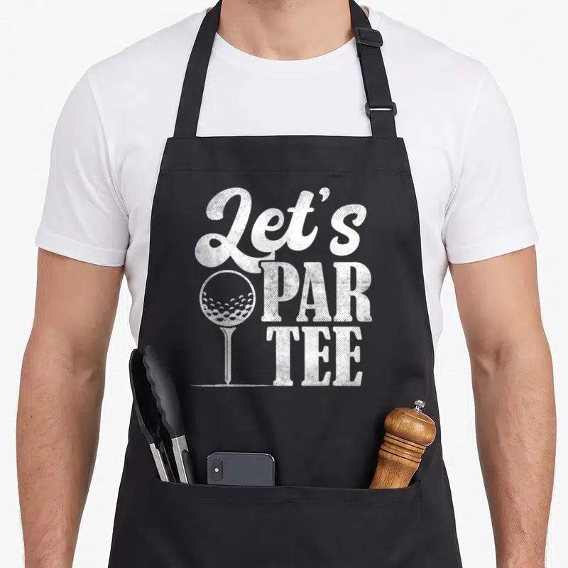 Par ball golf apron - White distressed Let's Par Tee text with golf ball on tee graphic — shown on a black cotton canvas apron against a white background