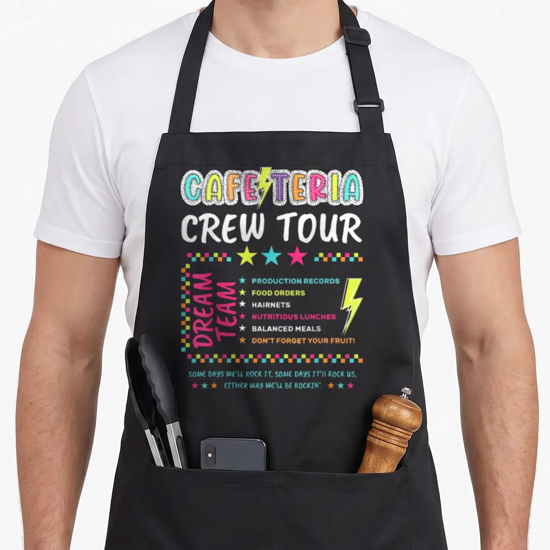 Crew lunch lady apron - Cafeteria crew tour text with dream team list and rockin slogan in cartoon style — shown on a black cotton canvas apron against a white background