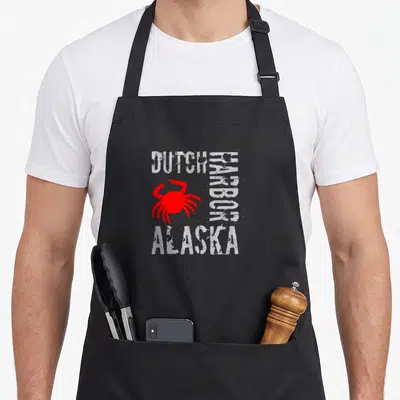 Alaska dutch apron - Red crab graphic with distressed white text DUTCH HARBOR ALASKA on black background — shown on a black cotton canvas apron against a white background