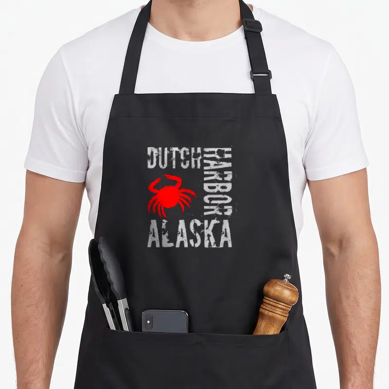 Alaska dutch apron - Red crab graphic with distressed white text DUTCH HARBOR ALASKA on black background — shown on a black cotton canvas apron against a white background