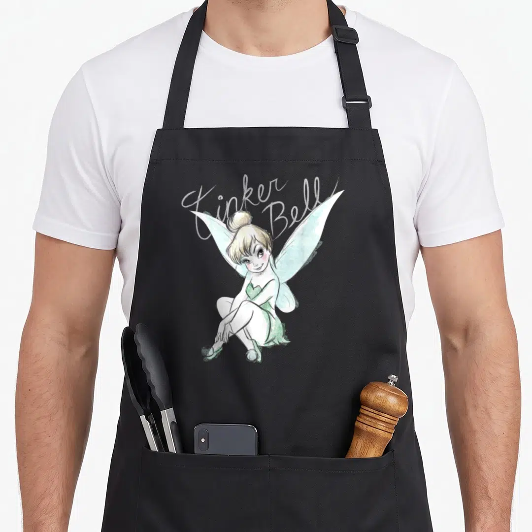 Sitting bell apron - Tinker Bell sitting in cartoon style with script text and pastel wings — shown on a black cotton canvas apron against a white background