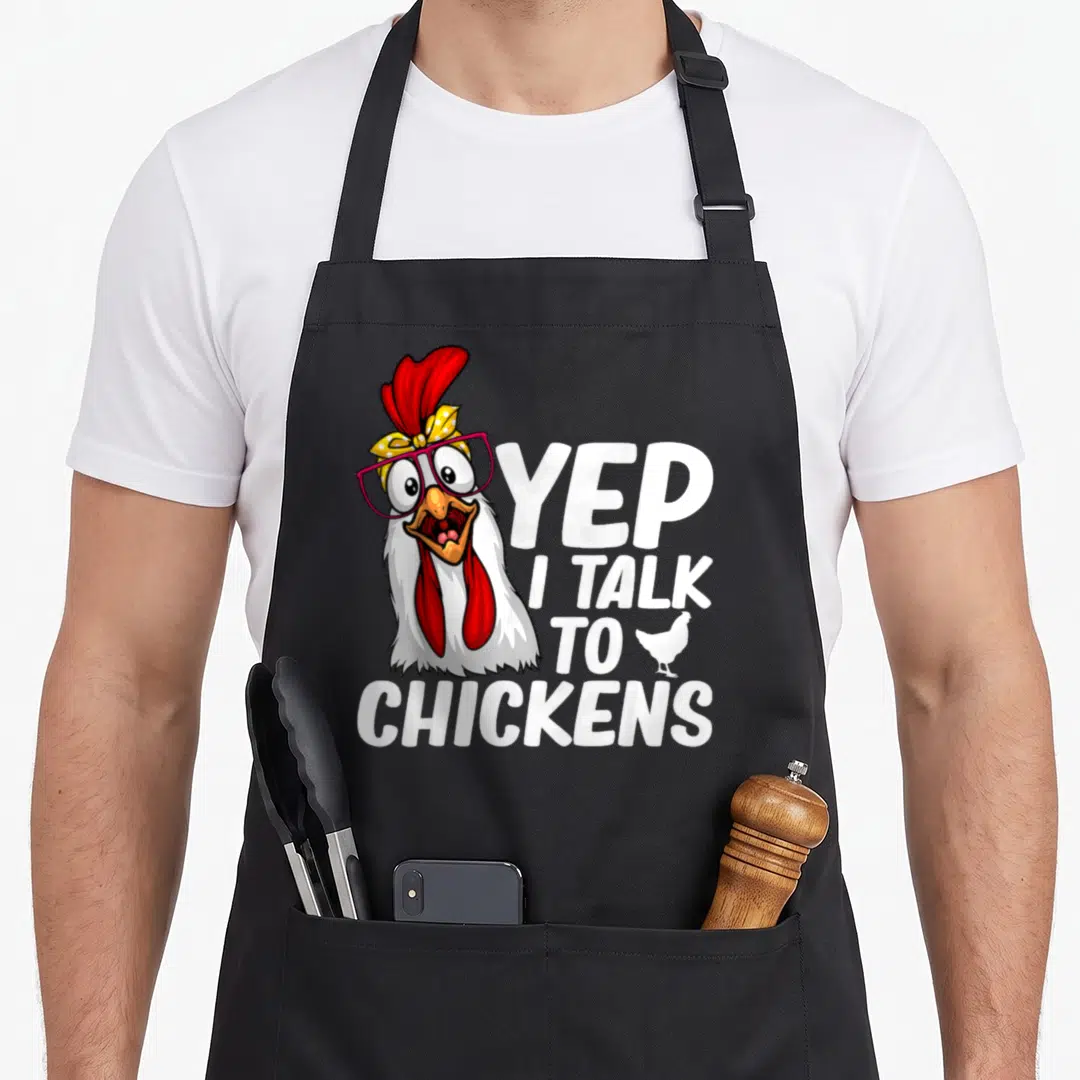 Vintage chicken farmer apron - Cartoon chicken head with glasses and text YEP I TALK TO CHICKENS — shown on a black cotton canvas apron against a white background
