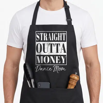 Straight money apron - White distressed typography reading STRAIGHT OUTTA MONEY Dance Mom with rectangular frames — shown on a black cotton canvas apron against a white background