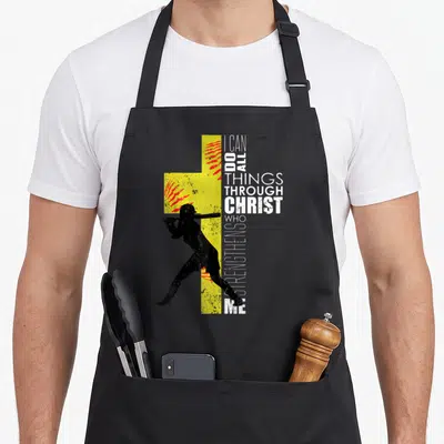 Player christian apron - Black baseball player silhouette over yellow cross with red splatters and vertical scripture — shown on a black cotton canvas apron against a white background