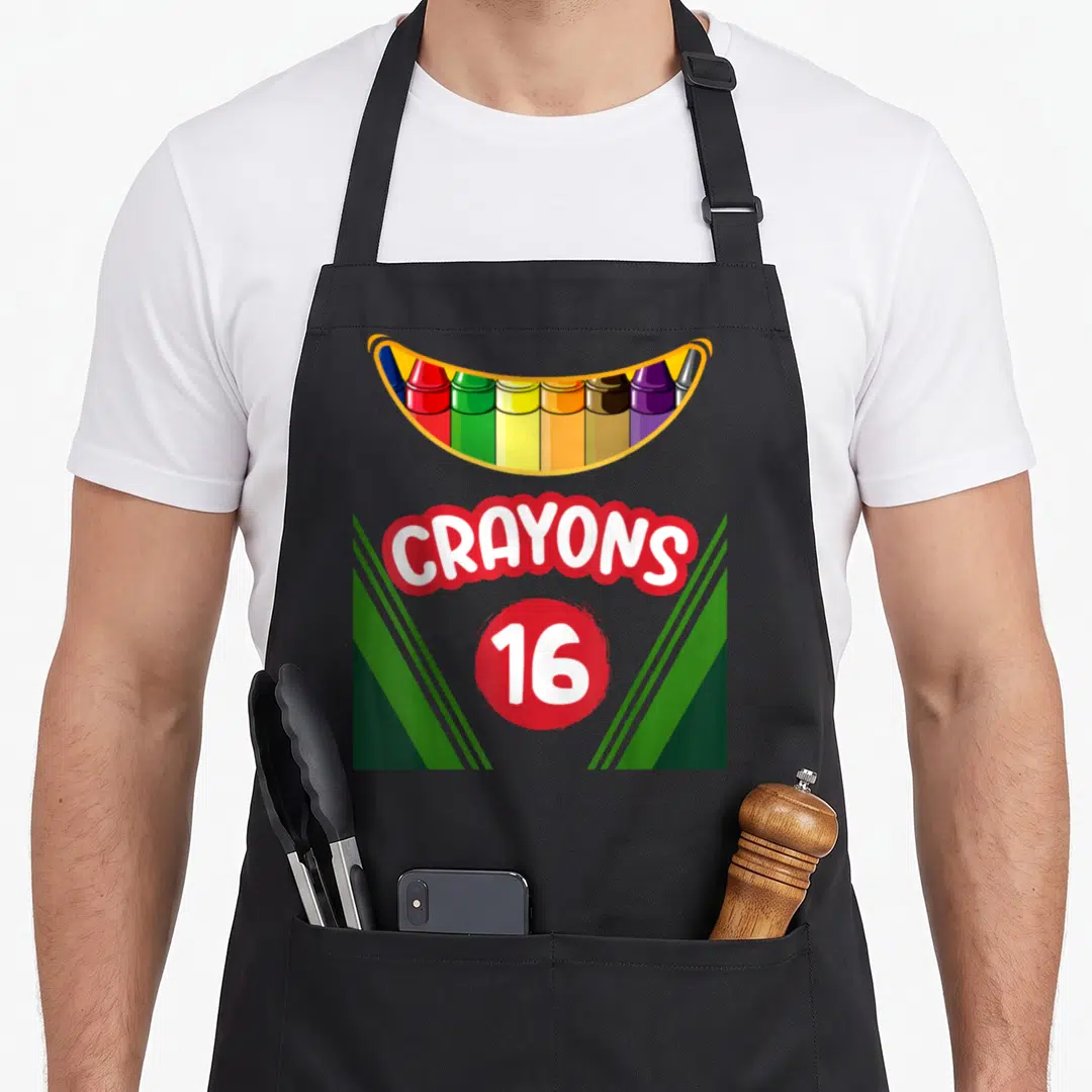 Box teacher apron - Cartoon crayon box graphic with red bubble text CRAYONS and number 16 flanked by green stripes — shown on a black cotton canvas apron against a white background