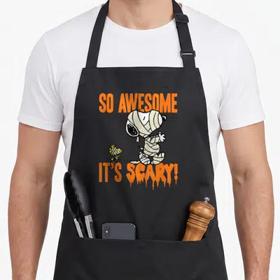 Scary mummy and me aprons - Snoopy and Woodstock mummy illustration with orange dripping text — shown on a black cotton canvas apron against a white background