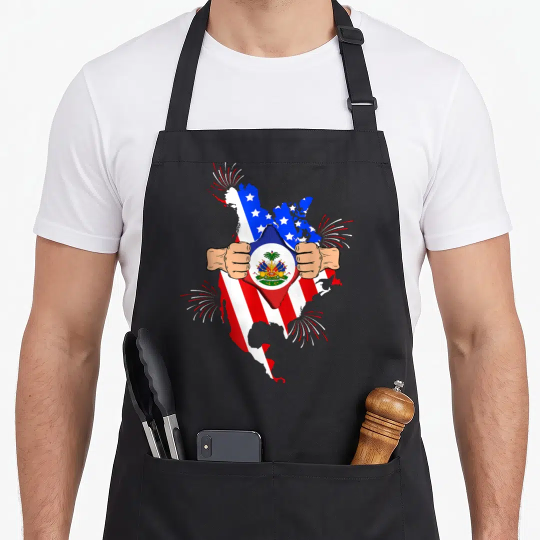 Haiti blood american flag apron - Two hands tearing a US flag map to reveal a Haitian flag map inside with fireworks — shown on a black cotton canvas apron against a white background