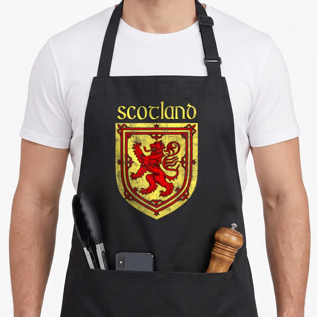 Rampant lion apron - Red lion rampant on yellow shield with scotland text in line art — shown on a black cotton canvas apron against a white background