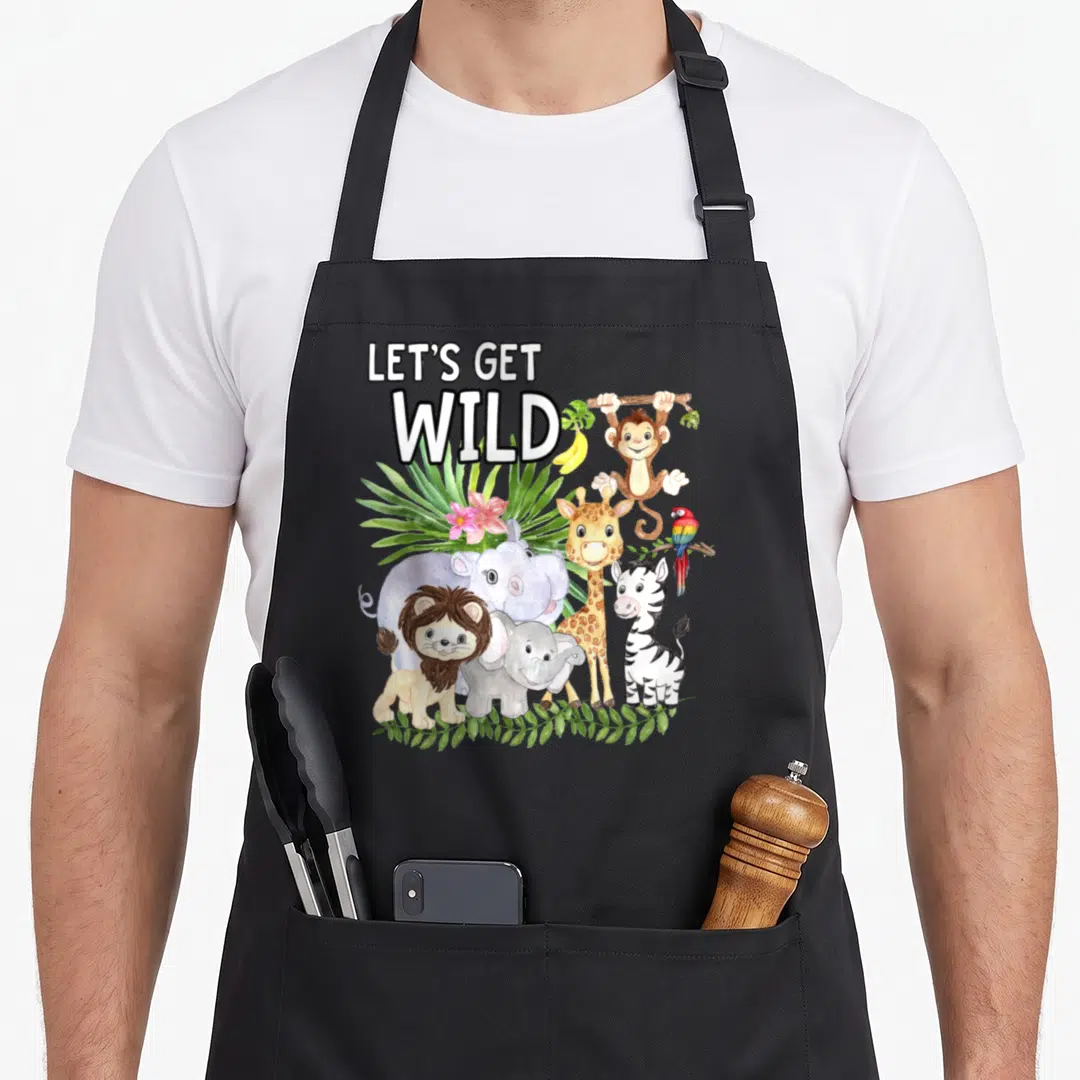 Wild animal apron - Let's Get Wild text above cartoon lion, zebra, giraffe, hippo, elephant, parrot, and hanging monkey — shown on a black cotton canvas apron against a white background