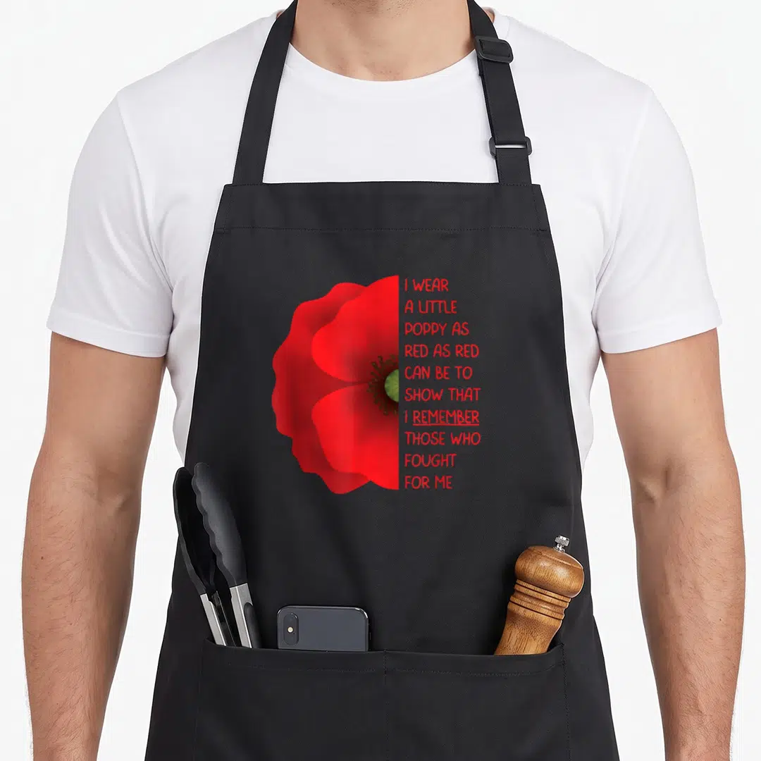 Veteran memorial day apron - Red poppy flower next to ten lines of red text reading I wear a little poppy as red as red — shown on a black cotton canvas apron against a white background
